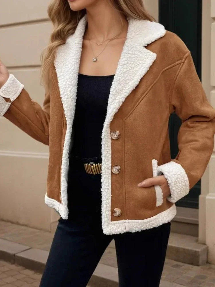 Woman holding a brown handbag while wearing a brown jacket with sherpa details.