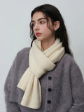 Side profile of a woman wearing a cream-colored ribbed knit scarf