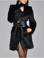 Woman wearing a black faux fur coat with a black leather belt cinched at the waist, front view