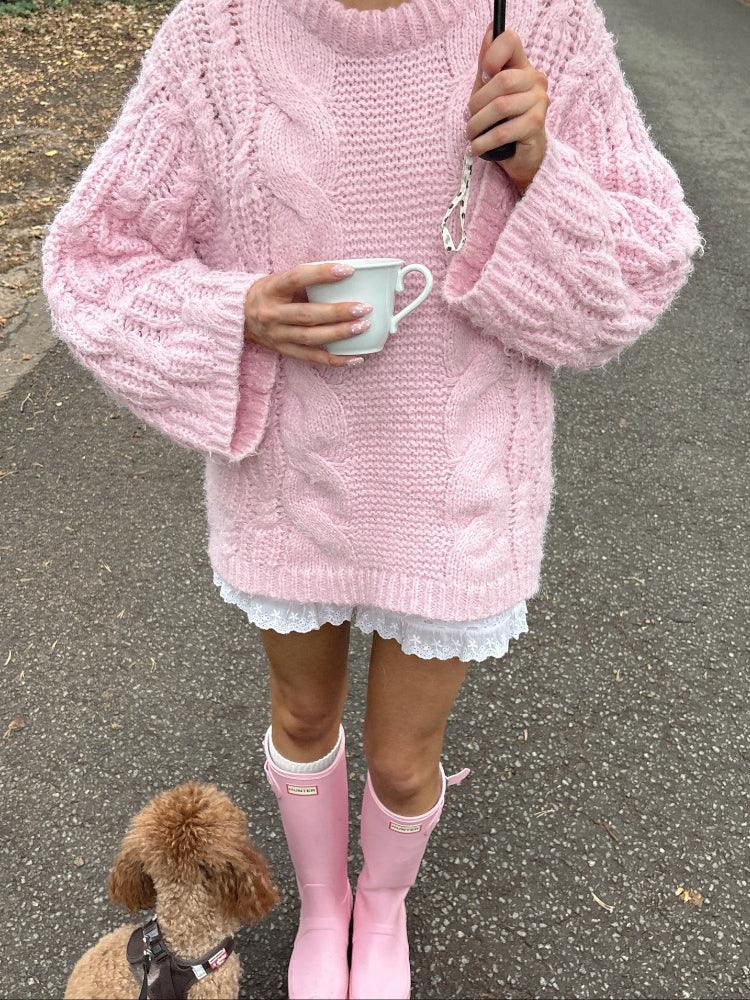 Woman holding a mug and umbrella in a pink chunky cable knit sweater Main image