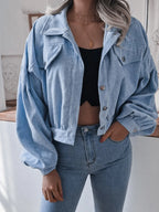 Front view of a woman in a light blue corduroy jacket, showing button details and pockets.