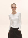 Model wearing a white long-sleeve ribbed knit top with a crew neckline.