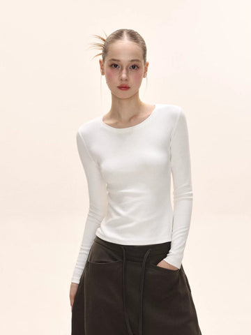Model wearing a white long-sleeve ribbed knit top with a crew neckline.