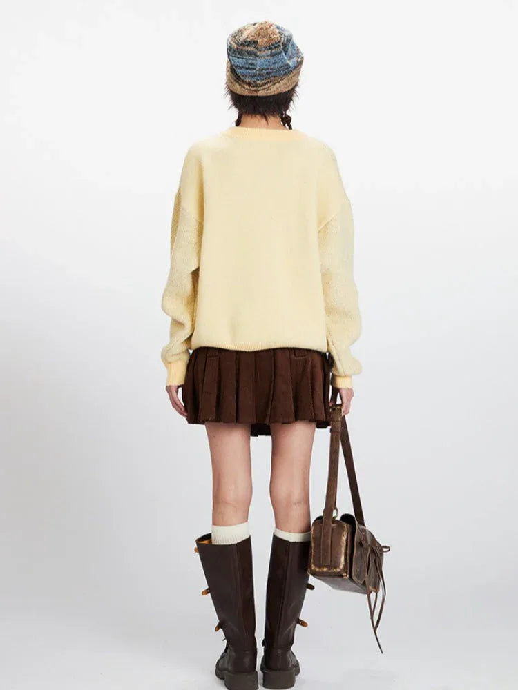 Back view of a woman wearing a yellow knit sweater with a horse graphic print, brown pleated skirt, white socks, and brown boots.
