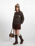 Full body shot of a woman in a casual outfit featuring a striped sweater and pleated skirt.