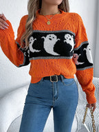 A woman poses in an orange knit sweater with a playful ghost design, suitable for casual occasions.