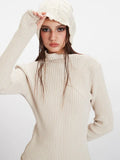 Close-up profile of a woman wearing a cream ribbed knit turtleneck sweater and a cream textured knit beanie.
