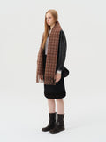 Side view of a woman with a brown tartan scarf draped around her neck