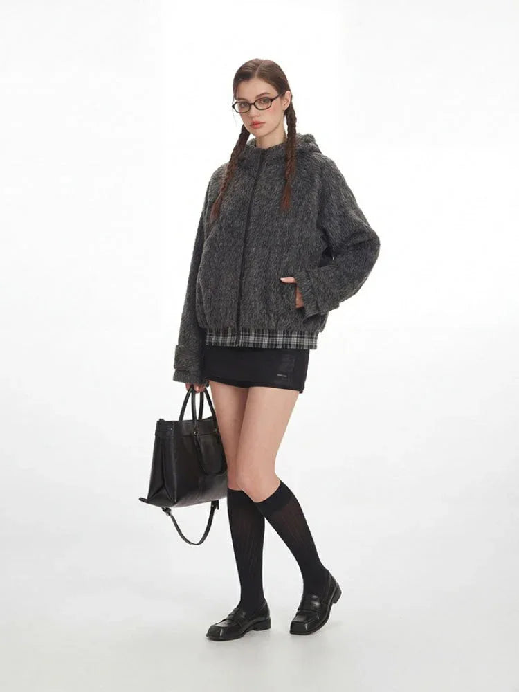 Full body shot of a woman modeling a grey bomber jacket with black accessories