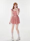 Full-body view of a woman in a red and white gingham dress, standing