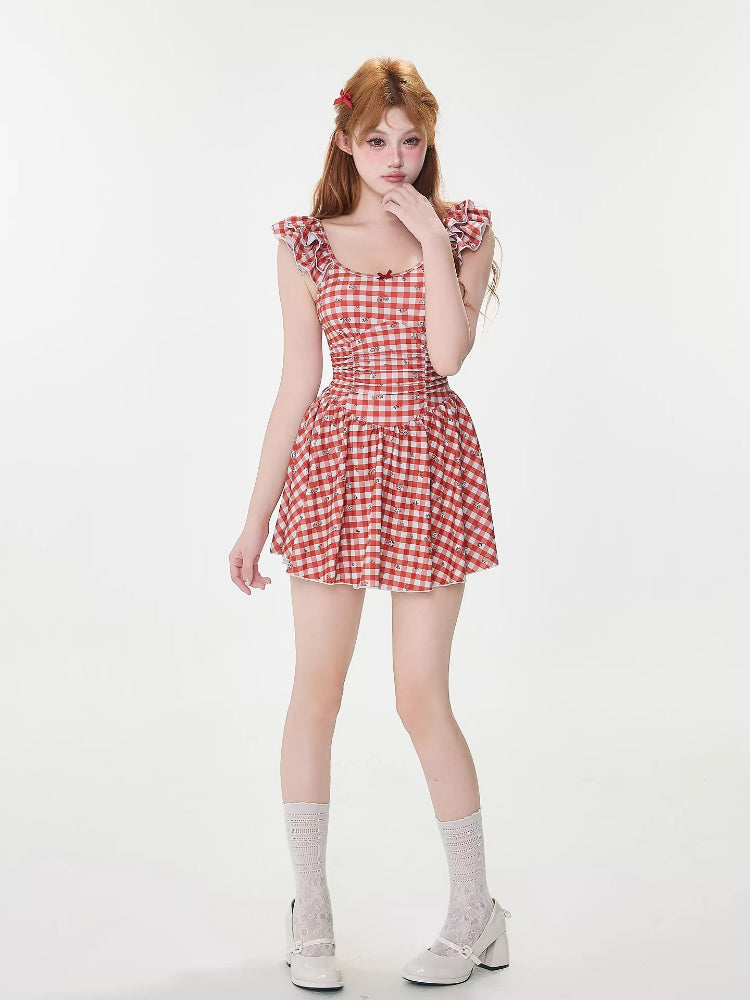 Full-body view of a woman in a red and white gingham dress, standing