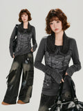 Full body shot of a woman in a dark gray graphic print top with ruched sleeves and a scarf collar, paired with distressed cargo pants.
