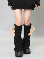 Black cable knit leg warmers with teddy bear embellishments, worn with a black hoodie and black platform sneakers.