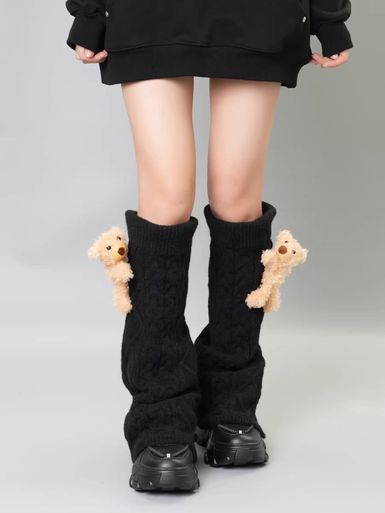 Black cable knit leg warmers with teddy bear embellishments, worn with a black hoodie and black platform sneakers.