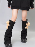 Black cable knit leg warmers with teddy bear embellishments, worn with a black hoodie and black platform sneakers.