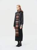 Woman wearing a black jacket and long skirt with a patterned scarf