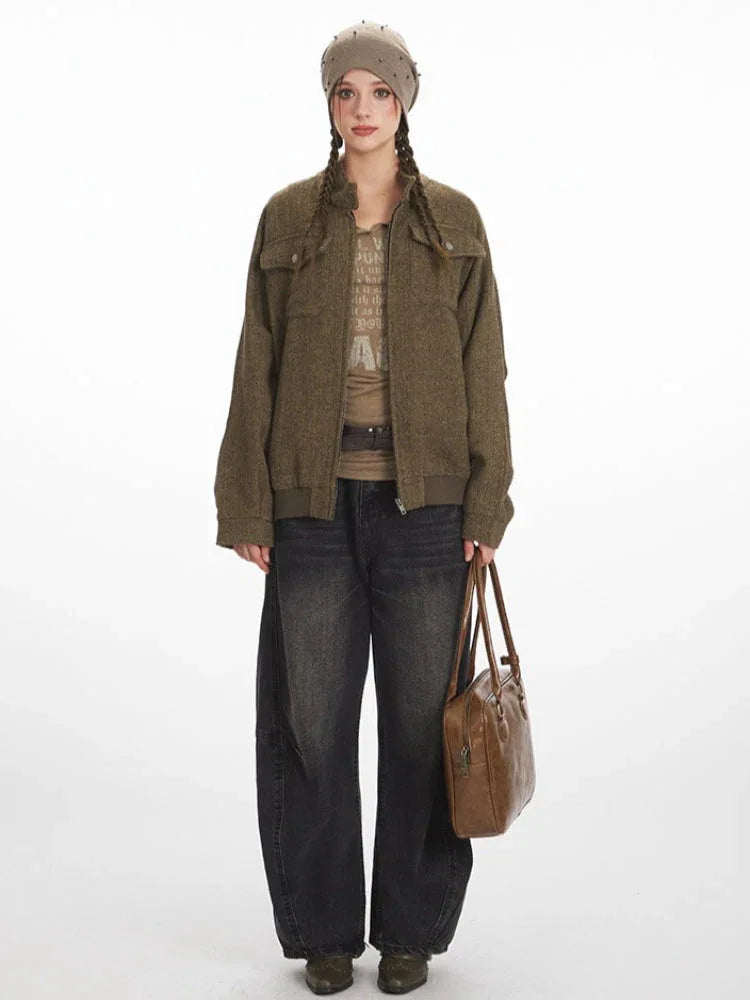 Woman wearing a brown herringbone bomber jacket with two chest pockets and a zipper front.