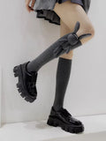 Close-up of grey knee-high socks featuring a detachable 3D bunny charm and a ribbed cuff.