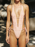 Front view of a pale pink ruched one-piece swimsuit with a plunging V-neckline and beaded waist tie