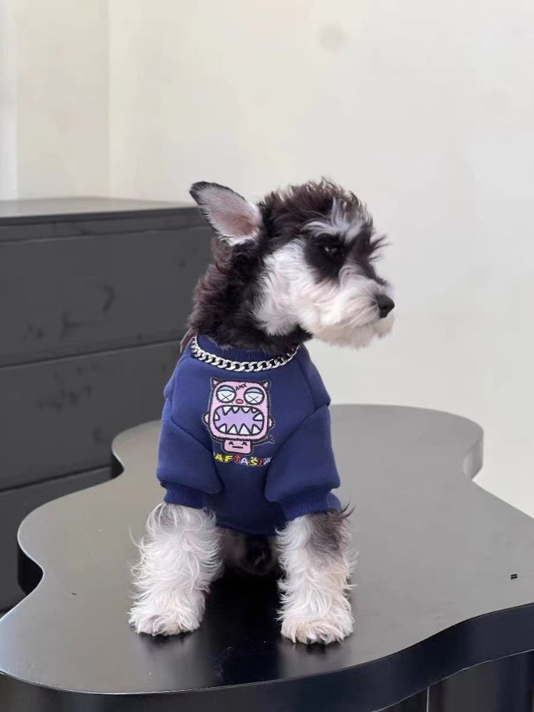 Side view of a miniature schnauzer puppy wearing a navy blue dog sweatshirt with a graphic print, looking to the right.