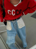 Detail of a white knit sweater with CCCP graphic print and striped hem.
