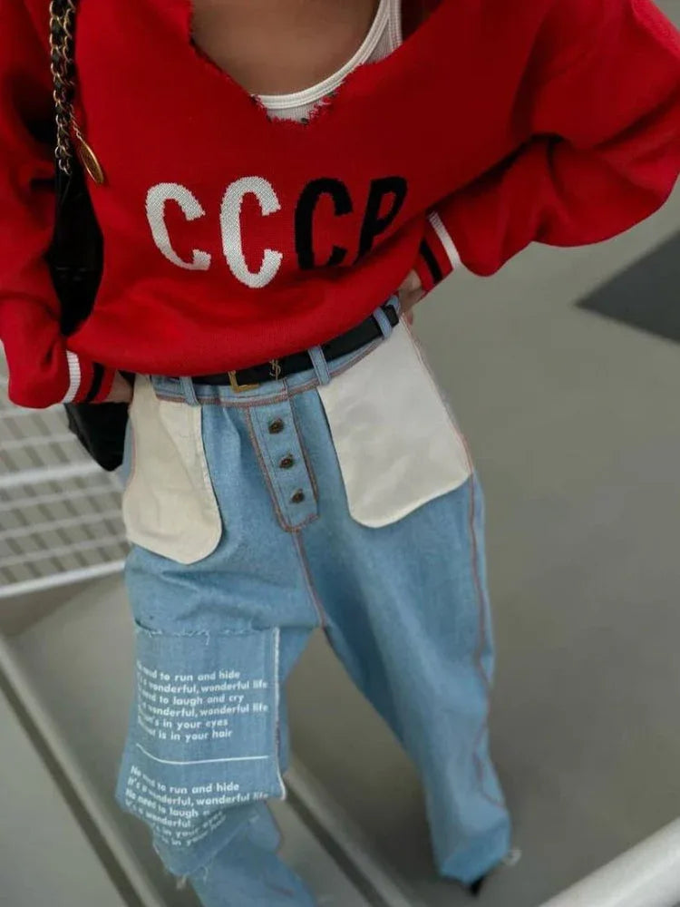 Detail of a white knit sweater with CCCP graphic print and striped hem.