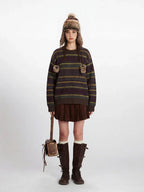 Woman wearing a striped knit sweater with faux fur pom-poms, a brown corduroy pleated skirt, white knee-high socks, brown leather boots, and a matching faux fur hat with ear flaps.