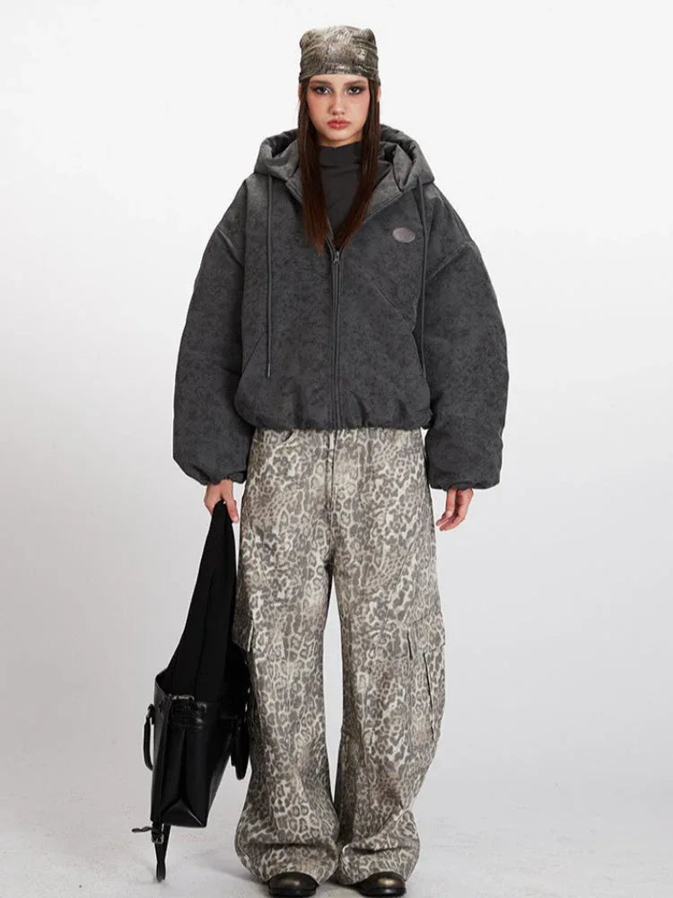 Woman wearing a charcoal grey textured puffer jacket with a hood and zipper closure.