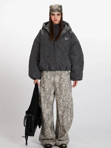 Woman wearing a charcoal grey textured puffer jacket with a hood and zipper closure.