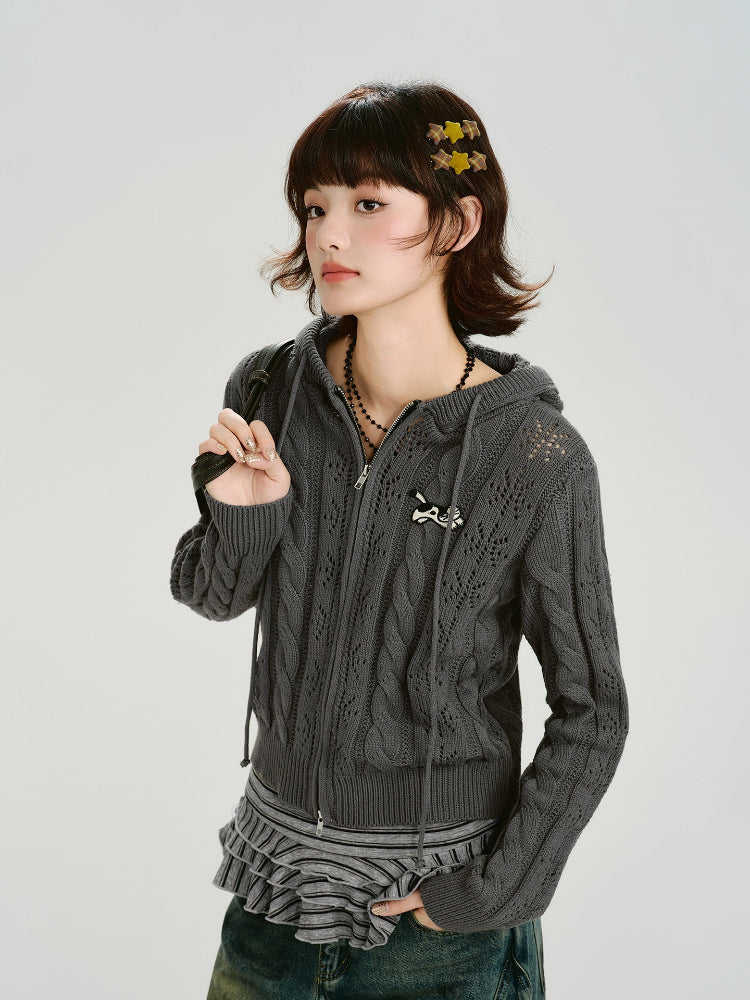 Model wearing a grey cable knit cropped hooded jacket with ear details and a zip closure.