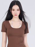 Close-up of the woman's face and the top of the brown swimsuit with plaid underlayer