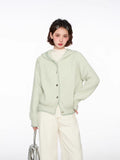 Woman wearing a light green hooded cardigan with a white top and cream wide-leg pants, holding a silver handbag.