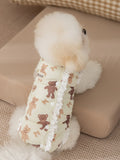 Rear view of a Bichon Frise dog wearing a light yellow padded vest with a teddy bear print.