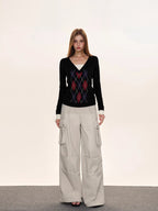Model posing in a black argyle V-neck knit sweater.