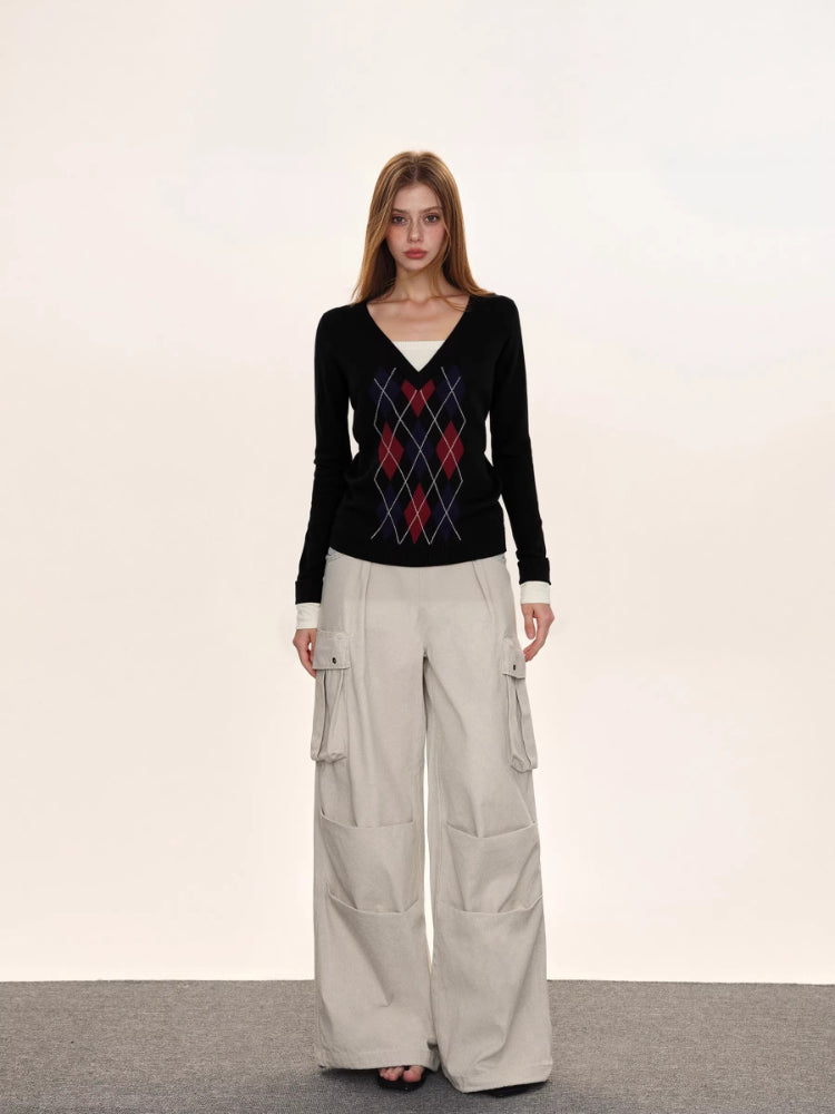 Model posing in a black argyle V-neck knit sweater.