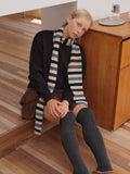 Knitted scarf with multicolor stripes draped over shoulders and lap