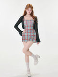Woman posing in a black sheer bell sleeve cardigan and a red and blue plaid spaghetti strap mini dress, showing off her outfit.