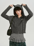 Model wearing a grey cable knit cropped hooded jacket with ear details and a zip closure.
