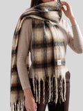 Woman styled with a warm plaid scarf over a cream coat