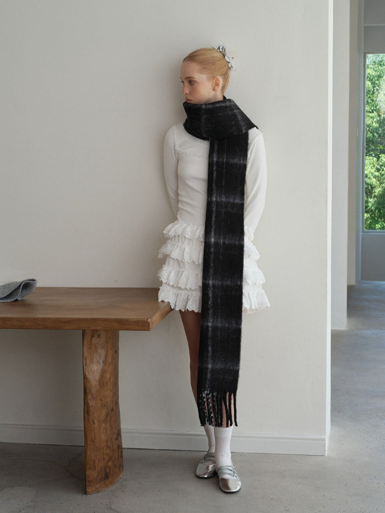woman wearing a black and grey tartan scarf draped around her neck