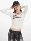 Close-up of a woman wearing a white long-sleeve graphic t-shirt with a scoop neckline and studded details.