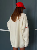 Back view of cream knit cardigan with red embroidered dachshund on sleeve