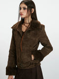 Woman showing the pocket of a brown faux suede jacket with shearling trim.
