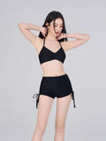 Woman wearing a black halter neck bikini top and ruched side bikini shorts