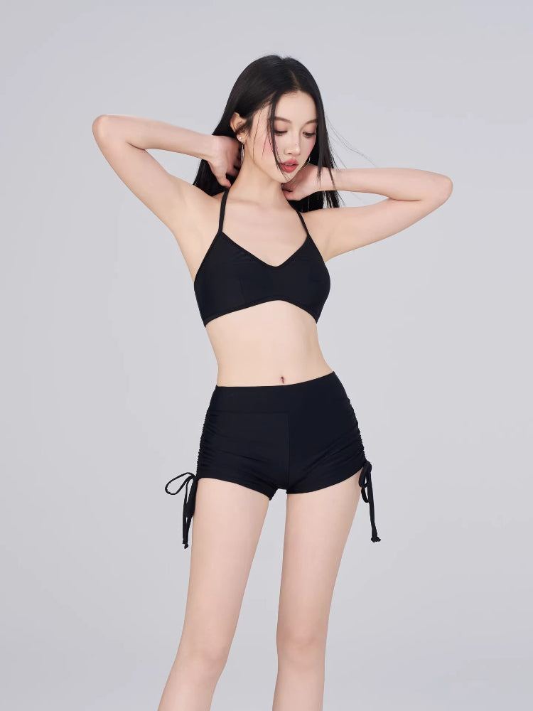 Woman wearing a black halter neck bikini top and ruched side bikini shorts