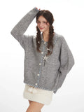 Close-up of the front of a grey knitted cardigan with decorative pendant
