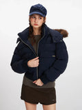 Close-up front view of a woman in a navy blue cropped puffer jacket, showing the zipper and pockets.