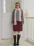 Woman wearing a gray sweatshirt, maroon skirt, white socks, black boots, and a pink fuzzy scarf with fringed ends.