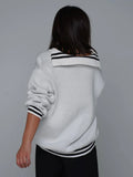 Woman wearing a red knit sweater with CCCP graphic print and black stripes on cuffs and hem.