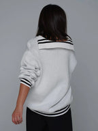 Woman wearing a red knit sweater with CCCP graphic print and black stripes on cuffs and hem.